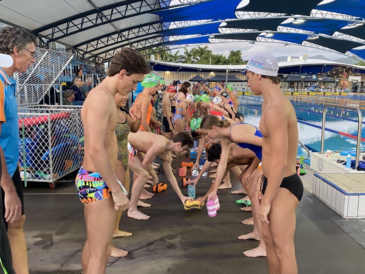 Group of young female and male swimmers participating in a game at swimming clinic