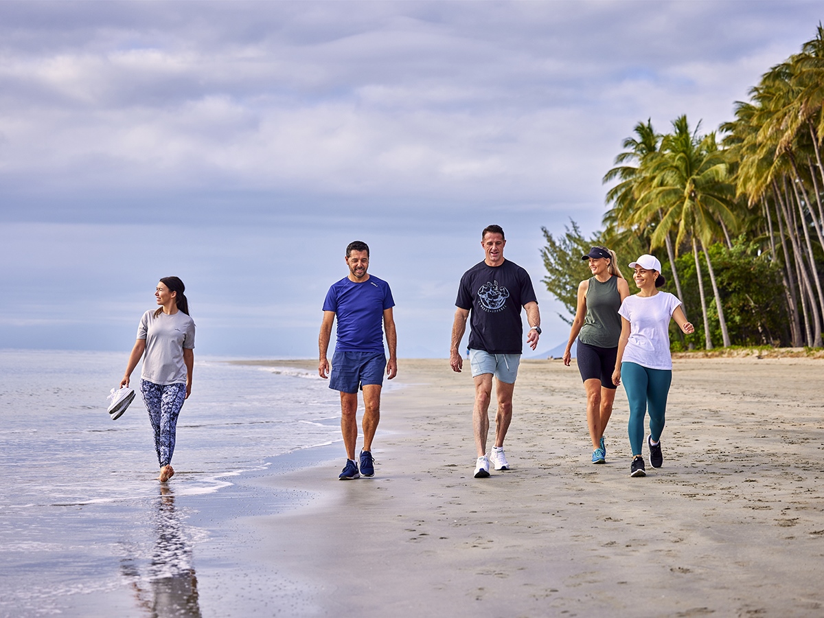 Group of men and women walking along a beach The sandy beach lined with palm trees