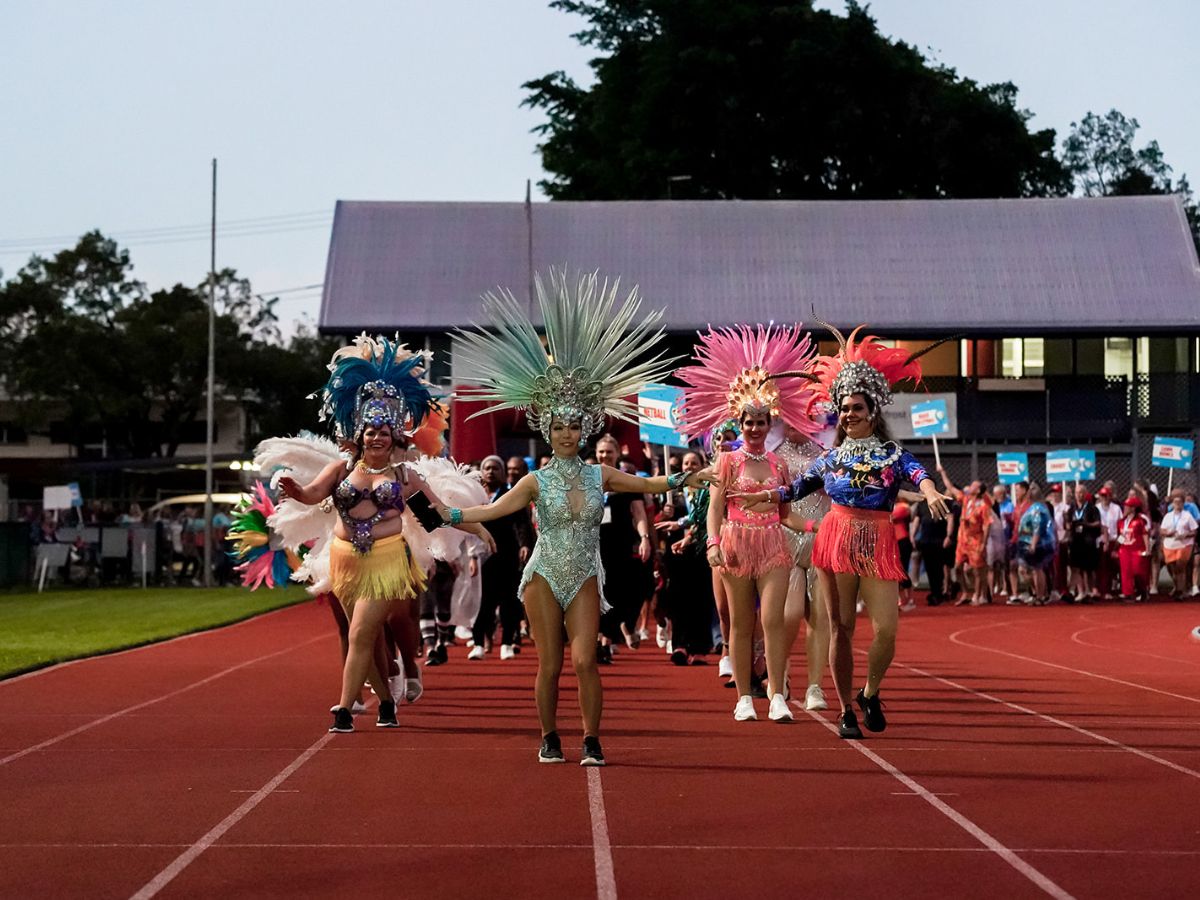 Salsa dancers leading the march past of competitors walking down an athletics track