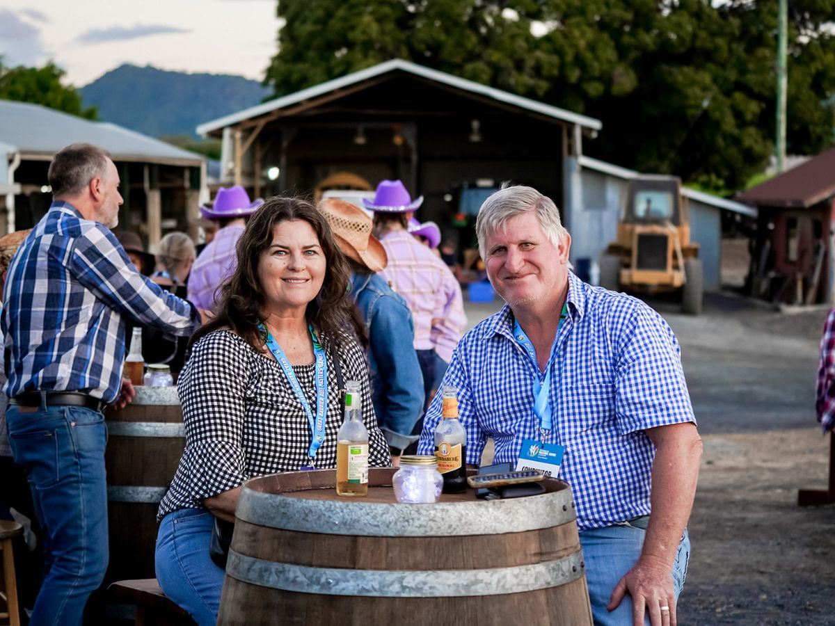 Couple sitting at wine barrel posing for a photo at a social event