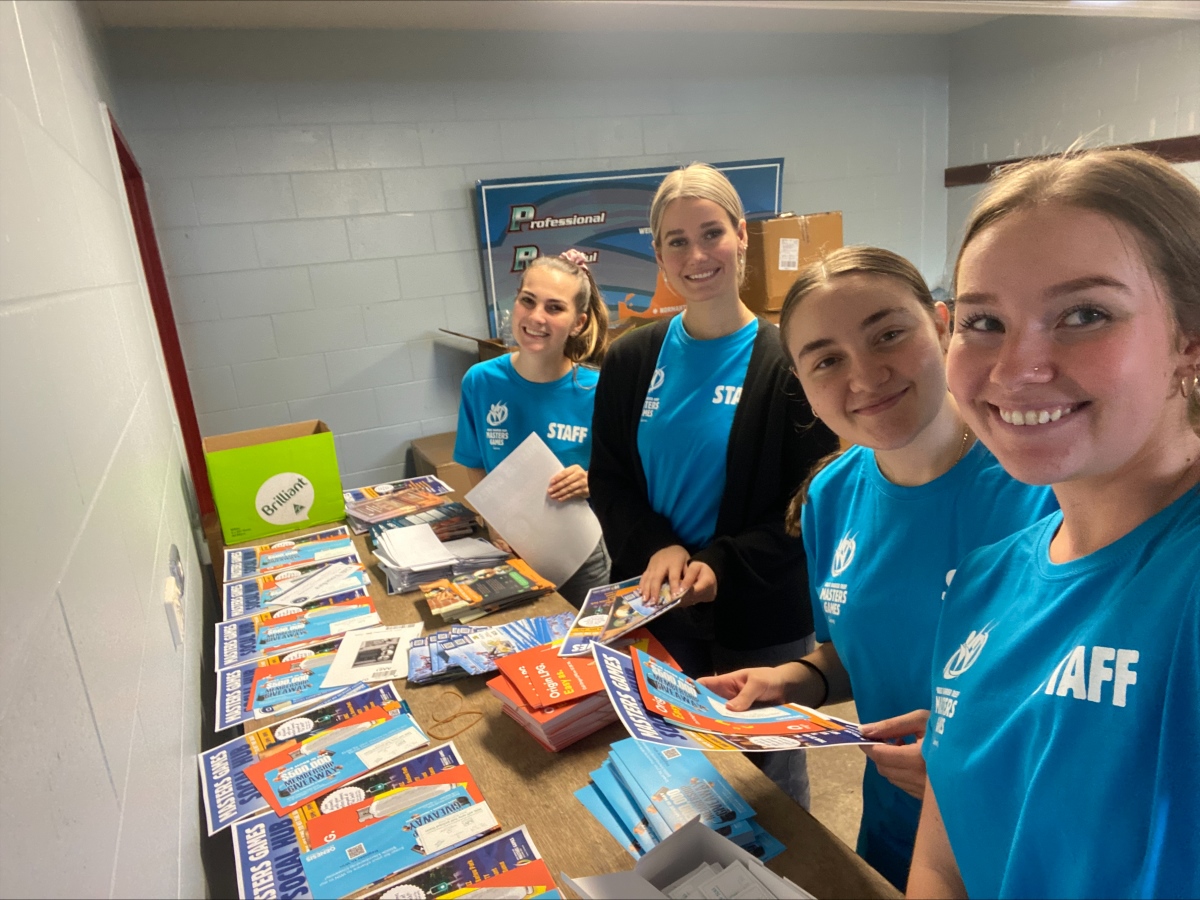 Group of volunteers smiling for a photo while packing competitor bags