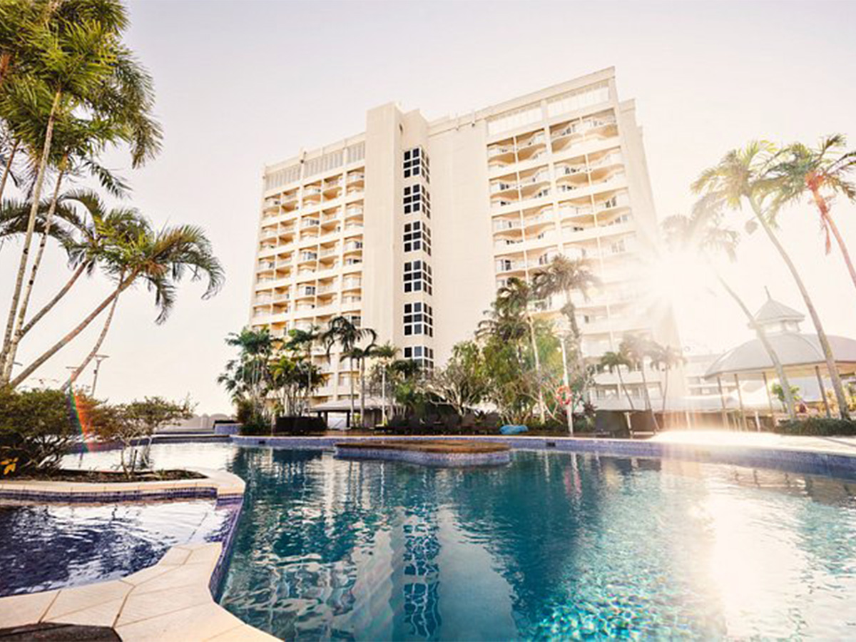 View of the Pullman Cairns International pool capturing its inviting blue waters surrounded by lush greenery