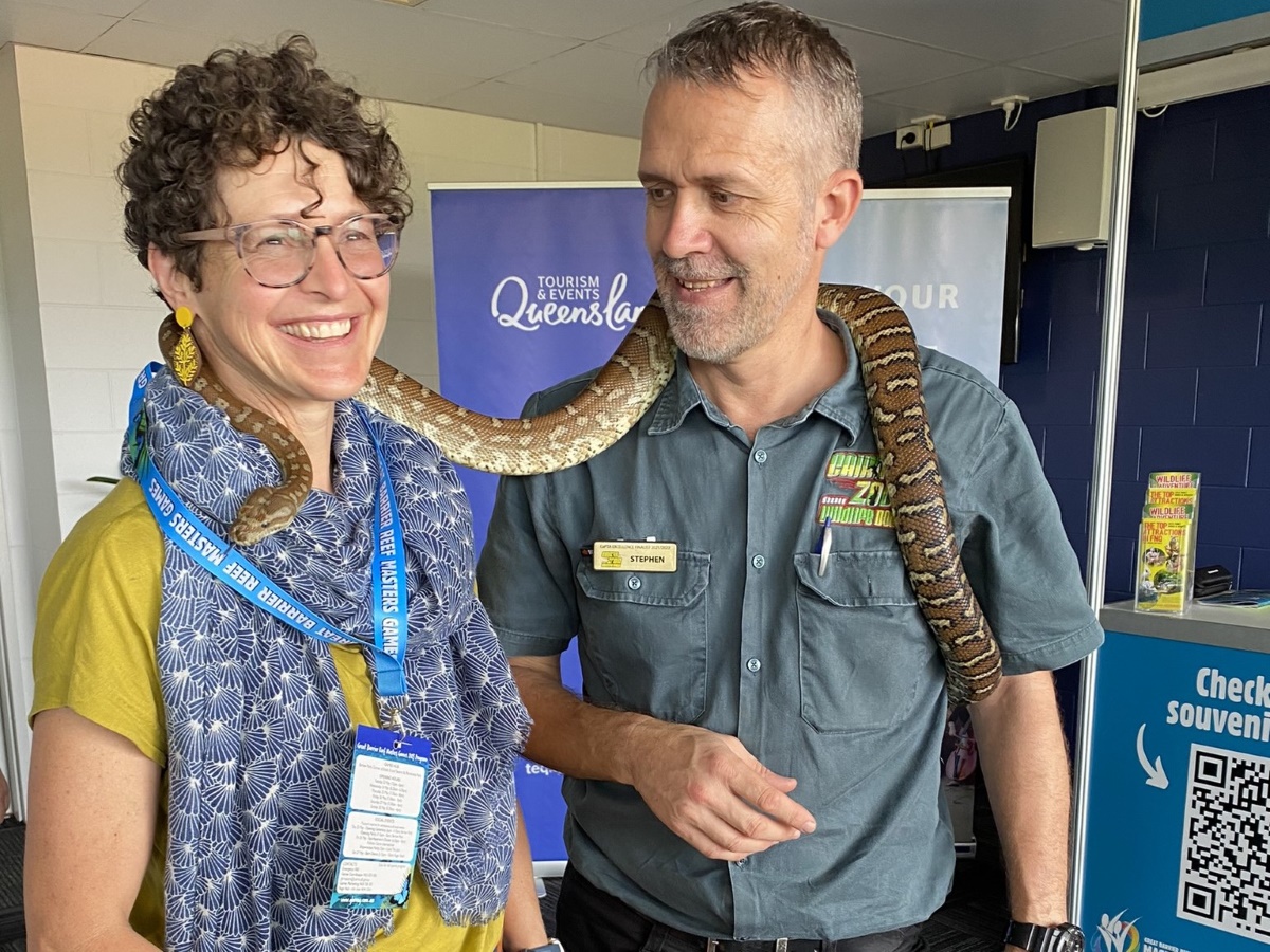 Man and a woman are posing with a snake at the registration hub